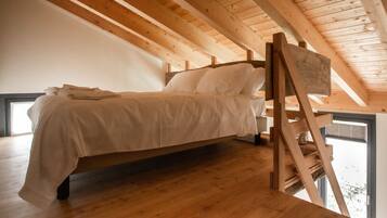 Une chambre de style « loft », avec un plafond en bois, un lit et une échelle.