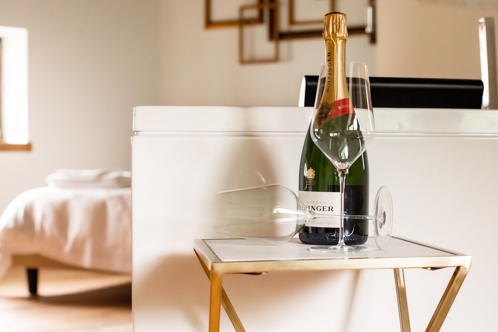 Una botella de champán Bollinger sobre una mesa pequeña con dos copas.