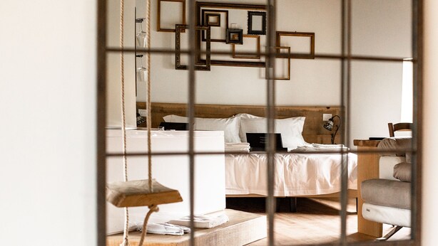 Une chambre à coucher comprenant un lit, une table de chevet, une chaise et un miroir.