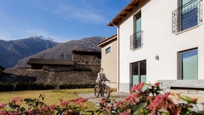 Une personne à vélo dans un quartier résidentiel, avec une chaîne de montagnes en arrière-plan.