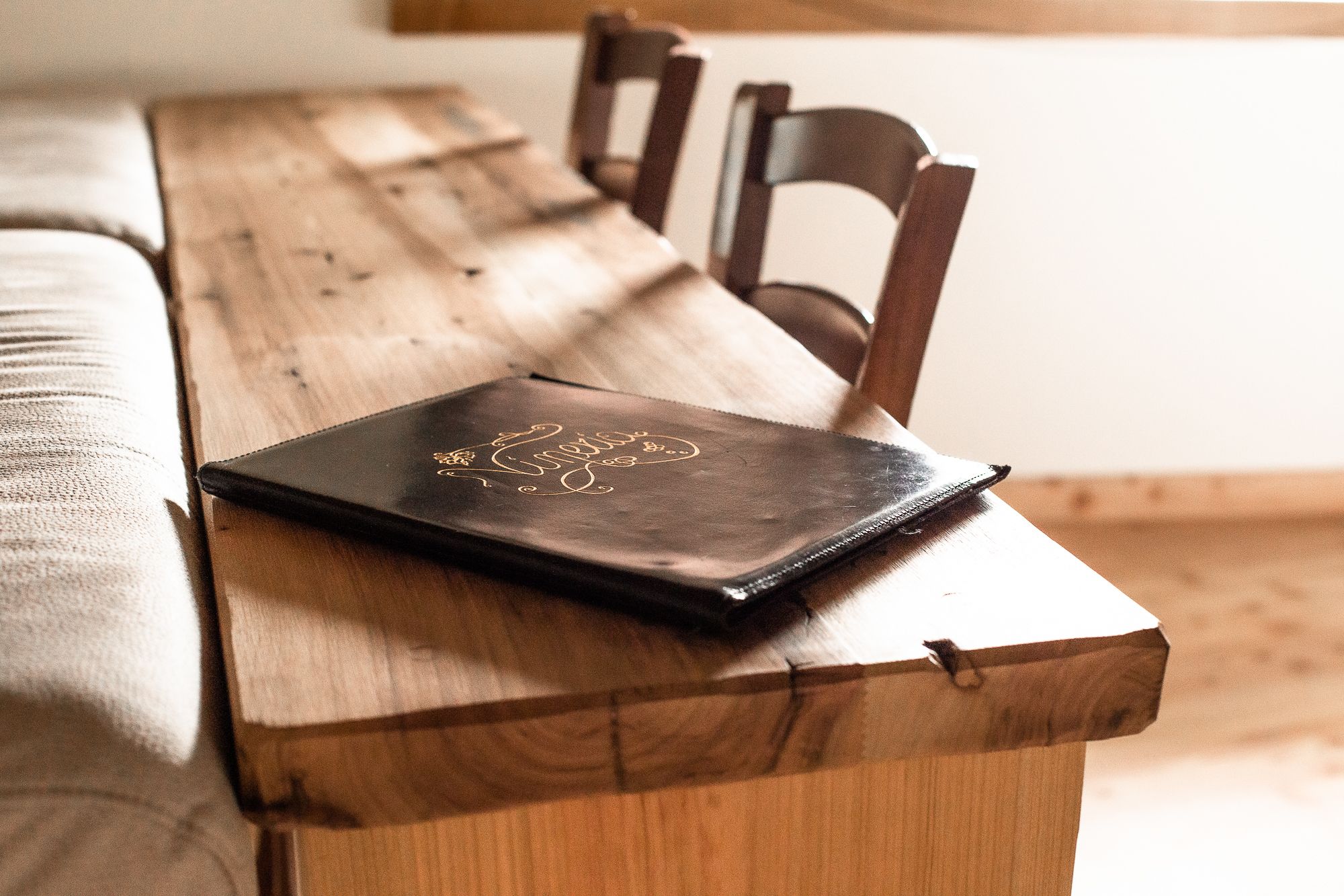 Una mesa de madera con un libro de tapa de cuero negra.
