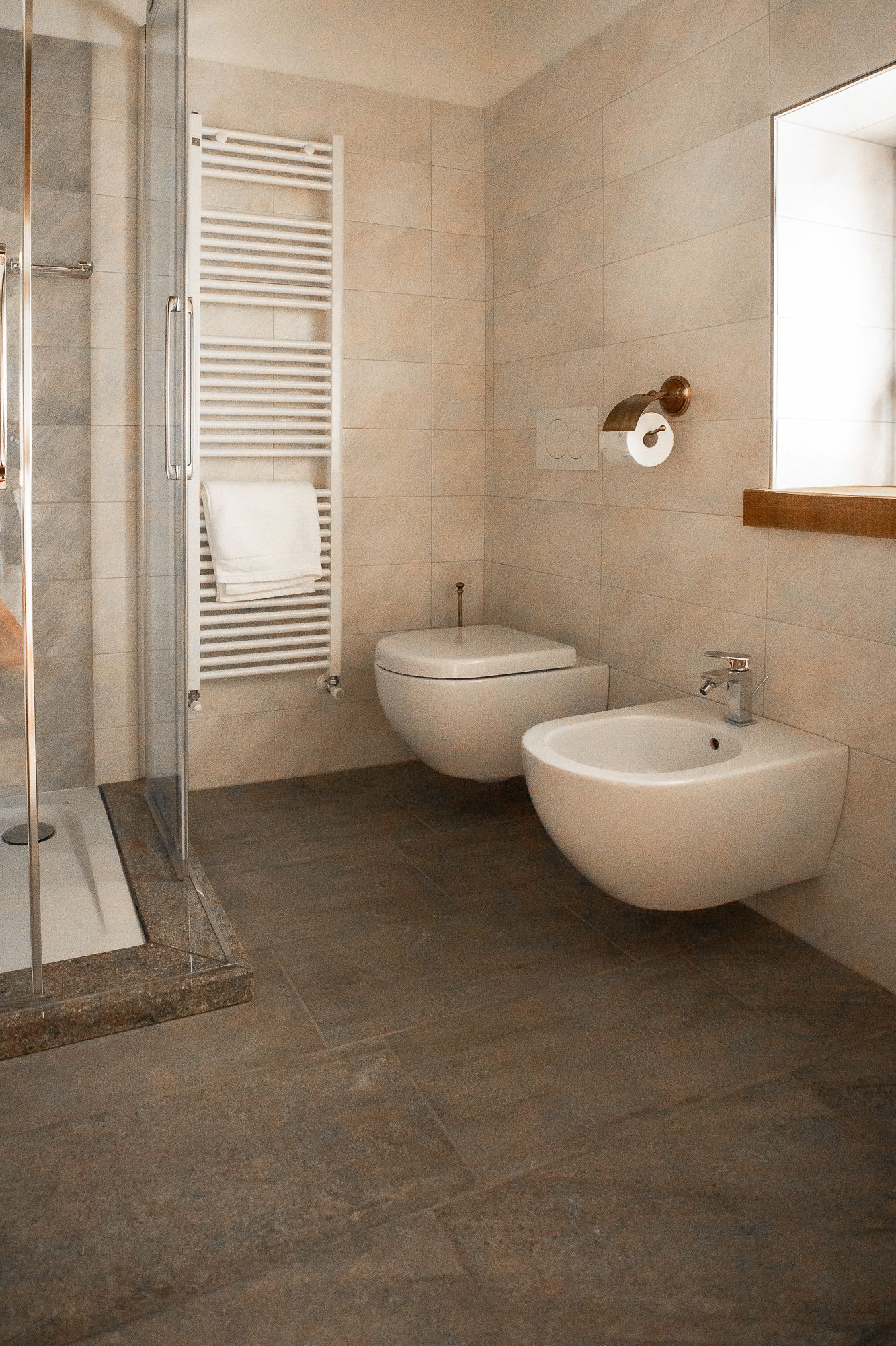 A bathroom with a glass shower enclosure, a toilet, and a sink.