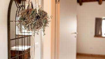 A hanging wooden ornament with dried flowers and greenery, a metal railing, and a wooden door in a room with white walls.