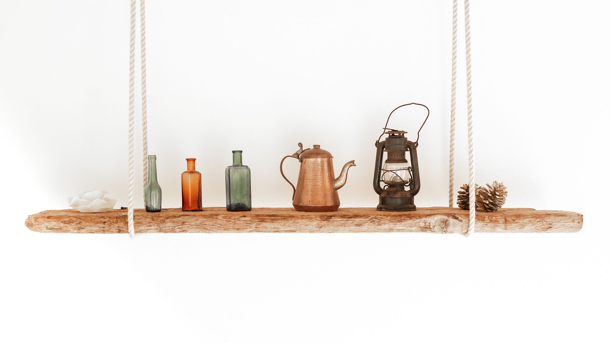 A rustic wooden shelf with various vintage items including bottles, a teapot, and a lantern.