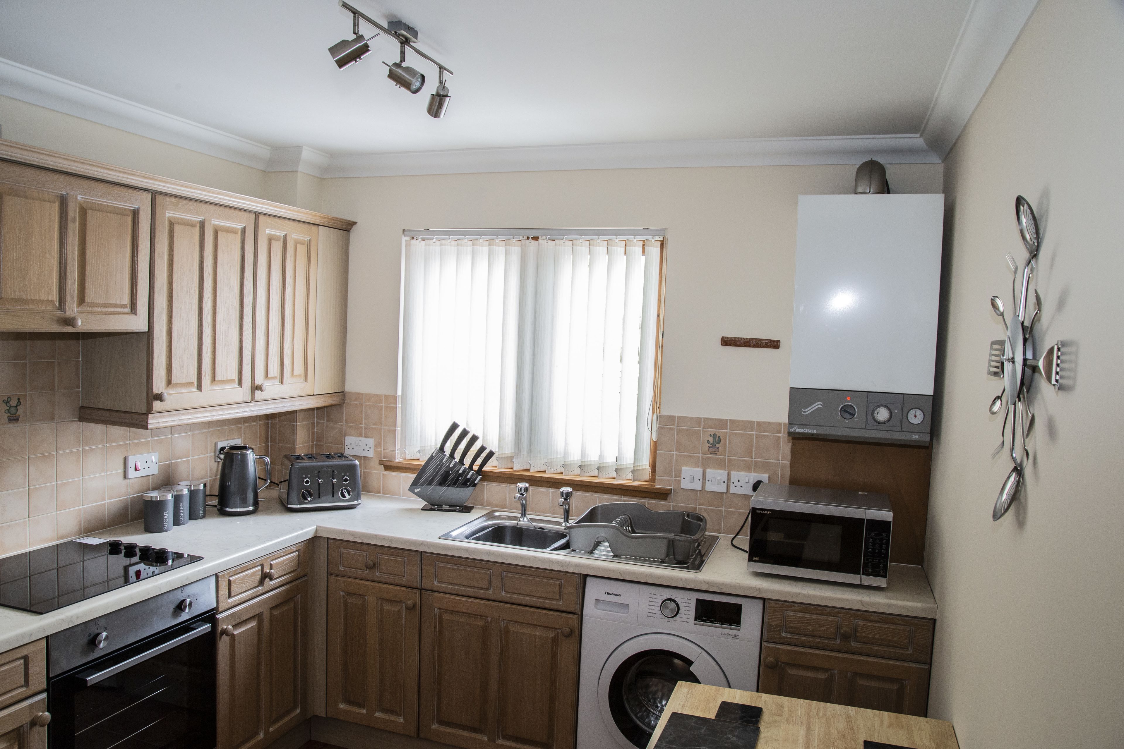 Una cocina con armarios de madera, lavadora, microondas y un lavabo.