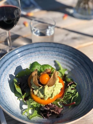 A salad with avocado, tomato, and greens on a blue plate. - Lugna Gården- Spa & Konferens (Löberöd)