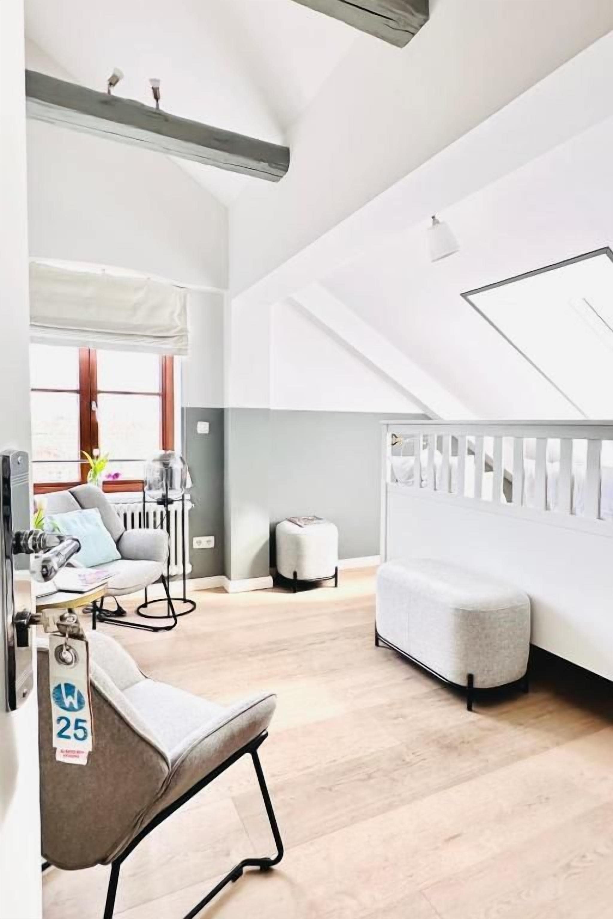 Een modern interieur met een hoge plafond, een trap, een zithoek met een stoel en een wandplank.