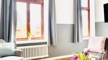 A room with a wooden table, a chair, a radiator, and a window with curtains.