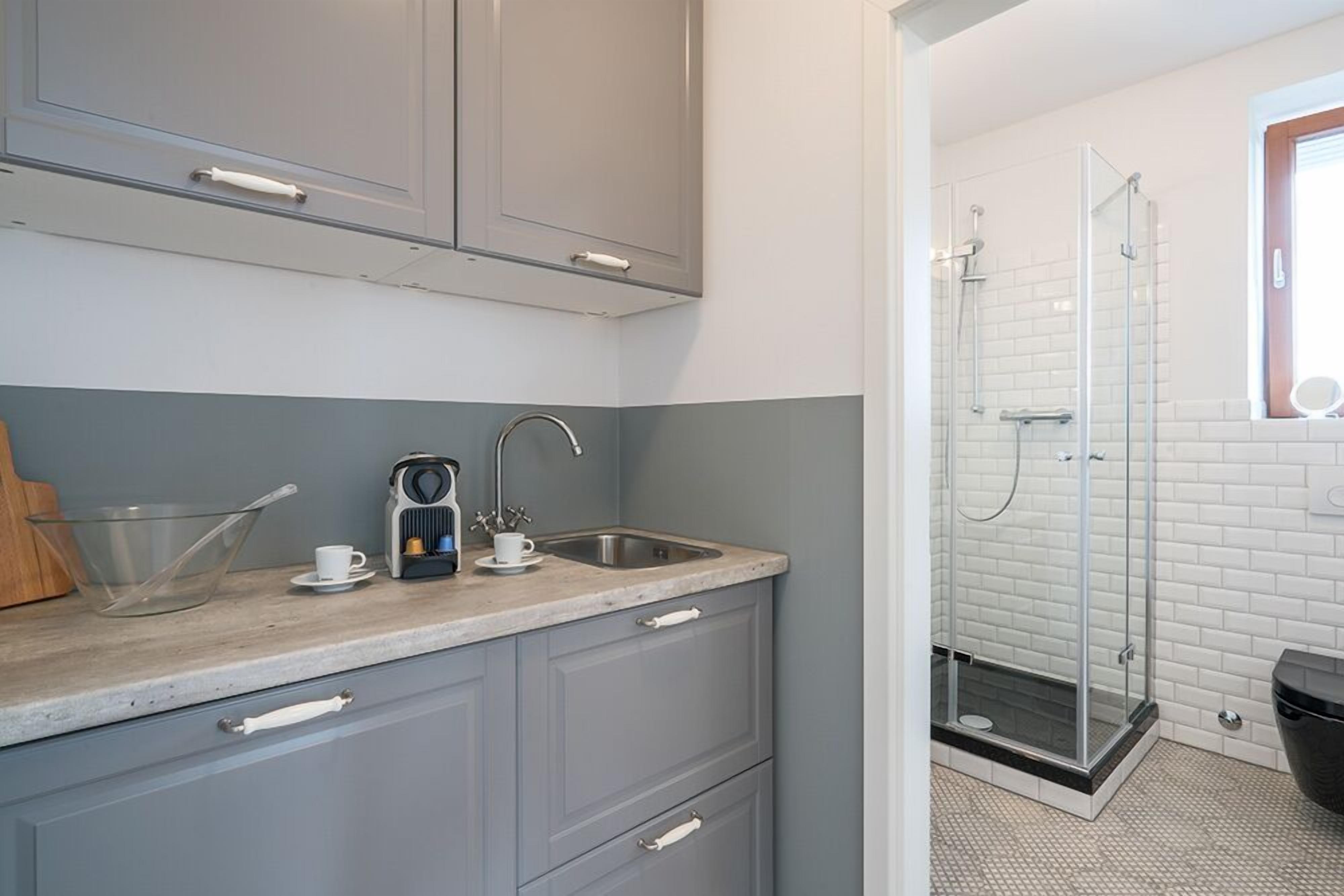 A modern kitchen with grey cabinets, a sink, and a coffee maker.