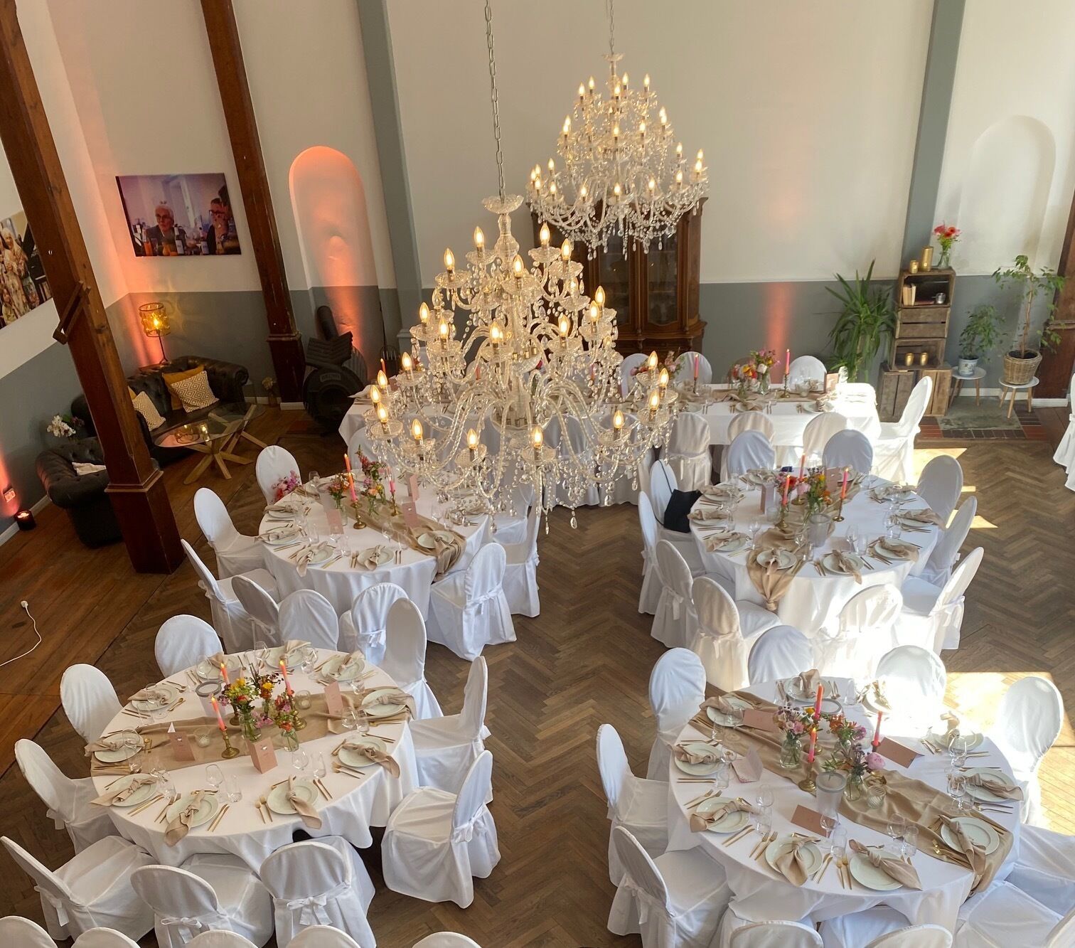 Un gran saló de banquets amb taules rodones preparades per a un esdeveniment formal, decorat amb estovalls blancs i una presentació de taula elegant.