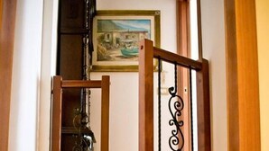 Uma escada de madeira com corrimão, um quadro acima e um armário embaixo.