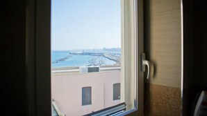 Quarto com janela que dá para uma área costeira, incluindo um cais e edifícios.