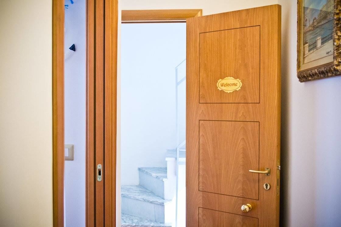 A wooden door with a welcome sign, a keyhole, and a handle.