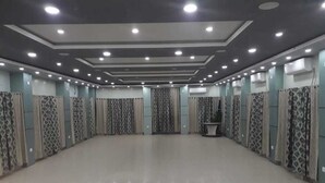 Une pièce spacieuse et bien éclairée, dotée d’un plancher ciré, de rideaux à motifs et d’un espace salon central.