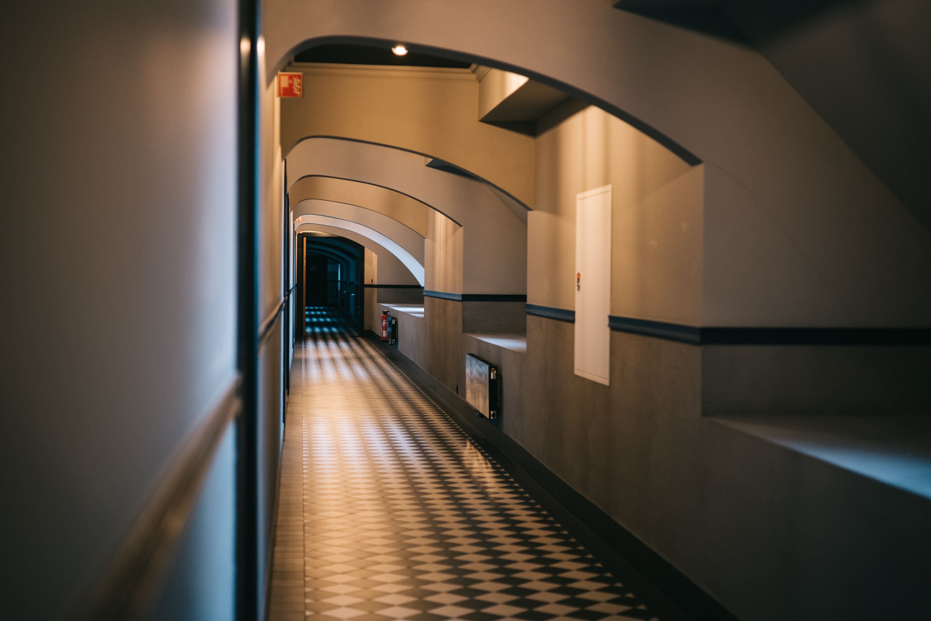 Un couloir doté d’un sol à carreaux, de murs incurvés et d’un escalier au bout.