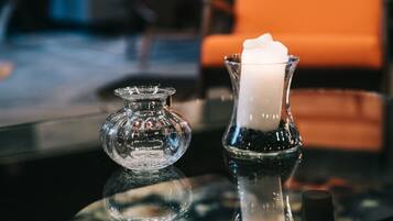 Un candelabro de vidrio con una vela blanca sobre una superficie reflectante.