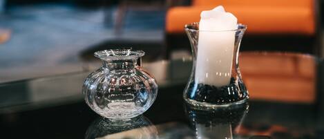 A glass candle holder with a white candle on a reflective surface.