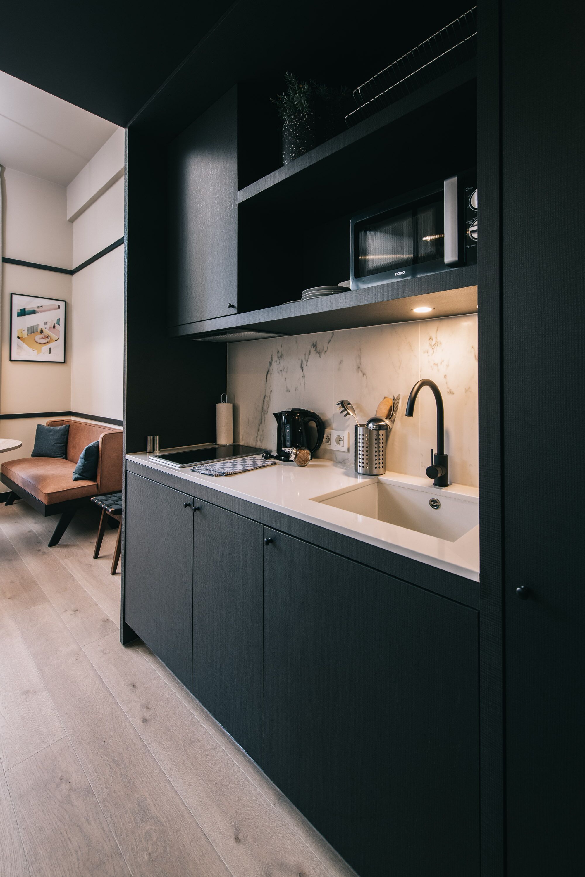 A modern kitchen with dark cabinetry, a white countertop, and a built-in microwave.