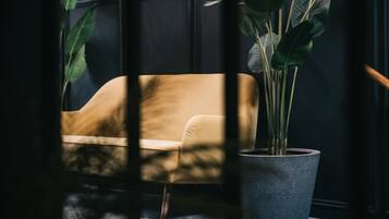 A room with a dark wooden paneled wall, a beige sofa, and a large potted plant.