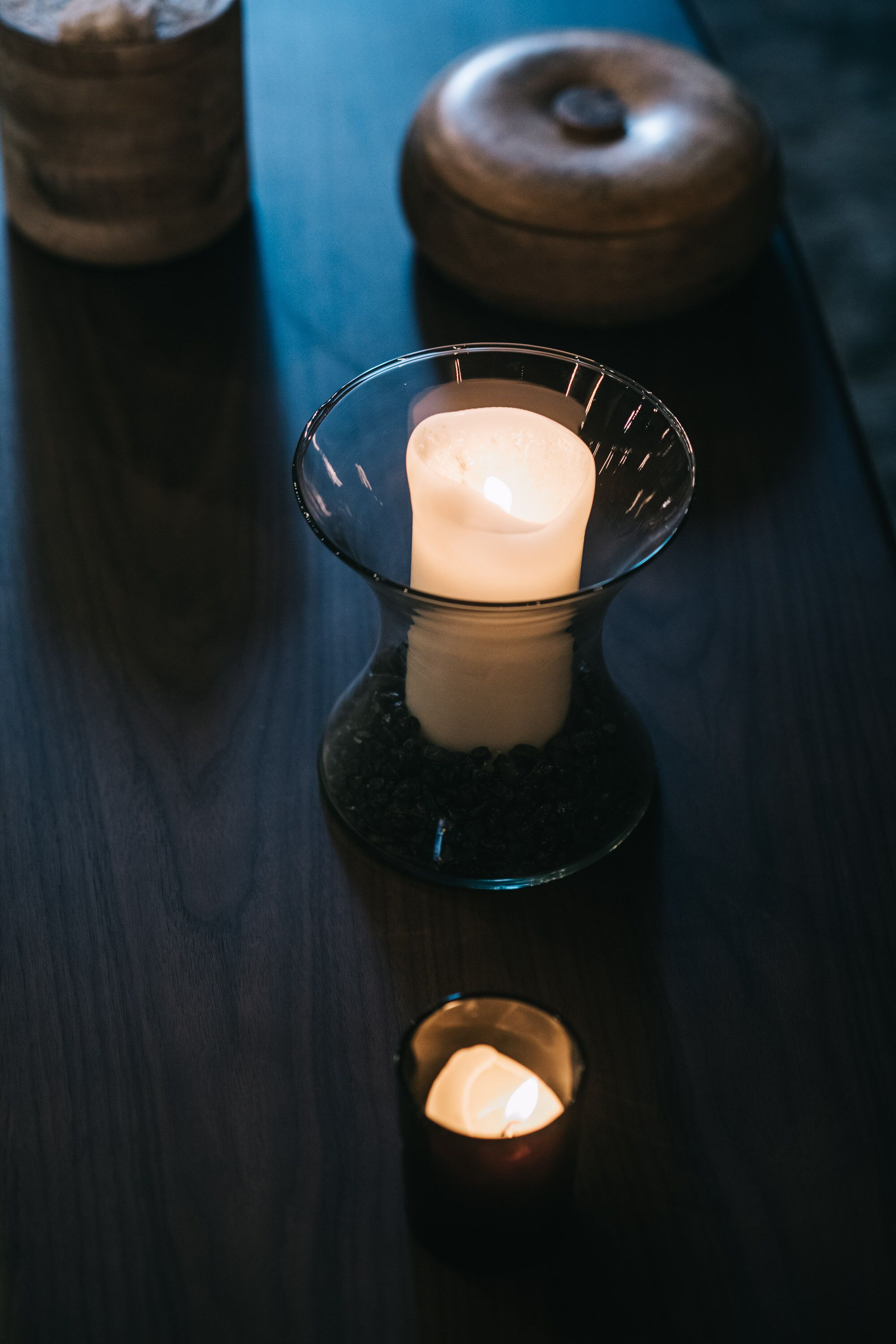 A candle in a glass holder on a wooden table.