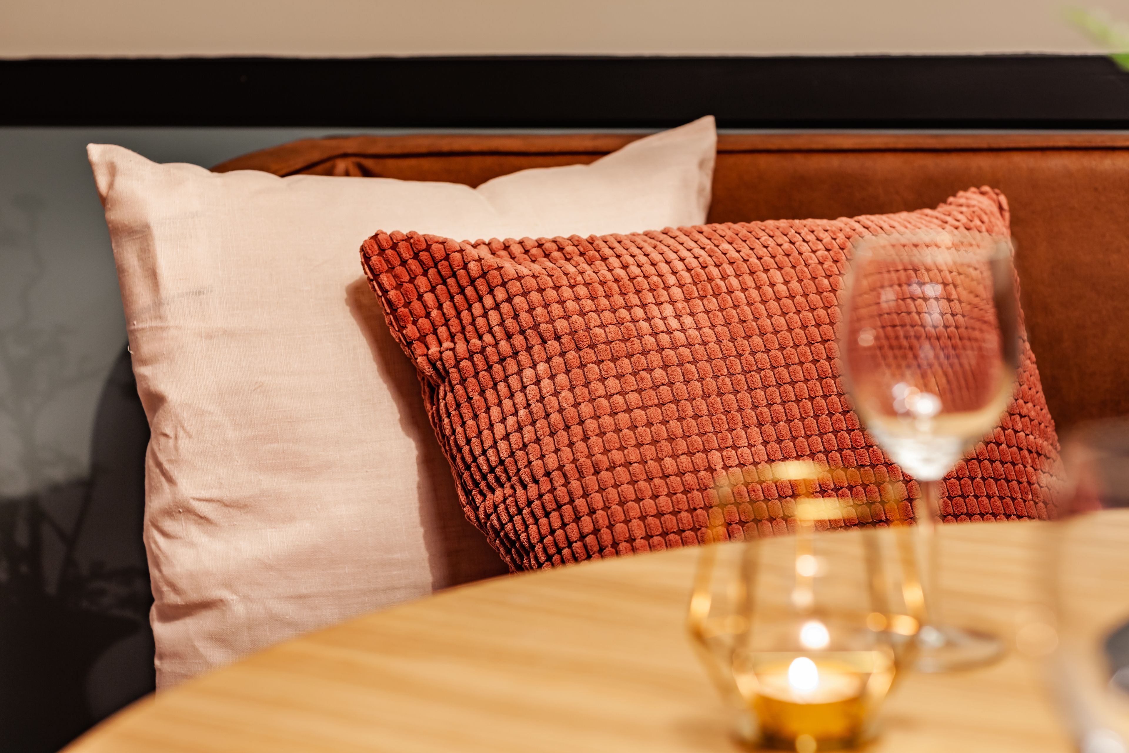 A cozy seating area with a wooden table, a glass of wine, and a candle.