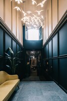 A modern interior with a central staircase, a yellow sofa, and a unique ceiling light fixture.