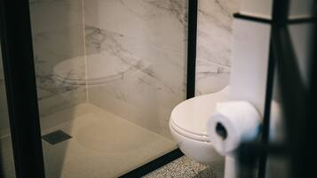 Un bagno con pavimento in marmo, un water e cabina doccia in vetro.