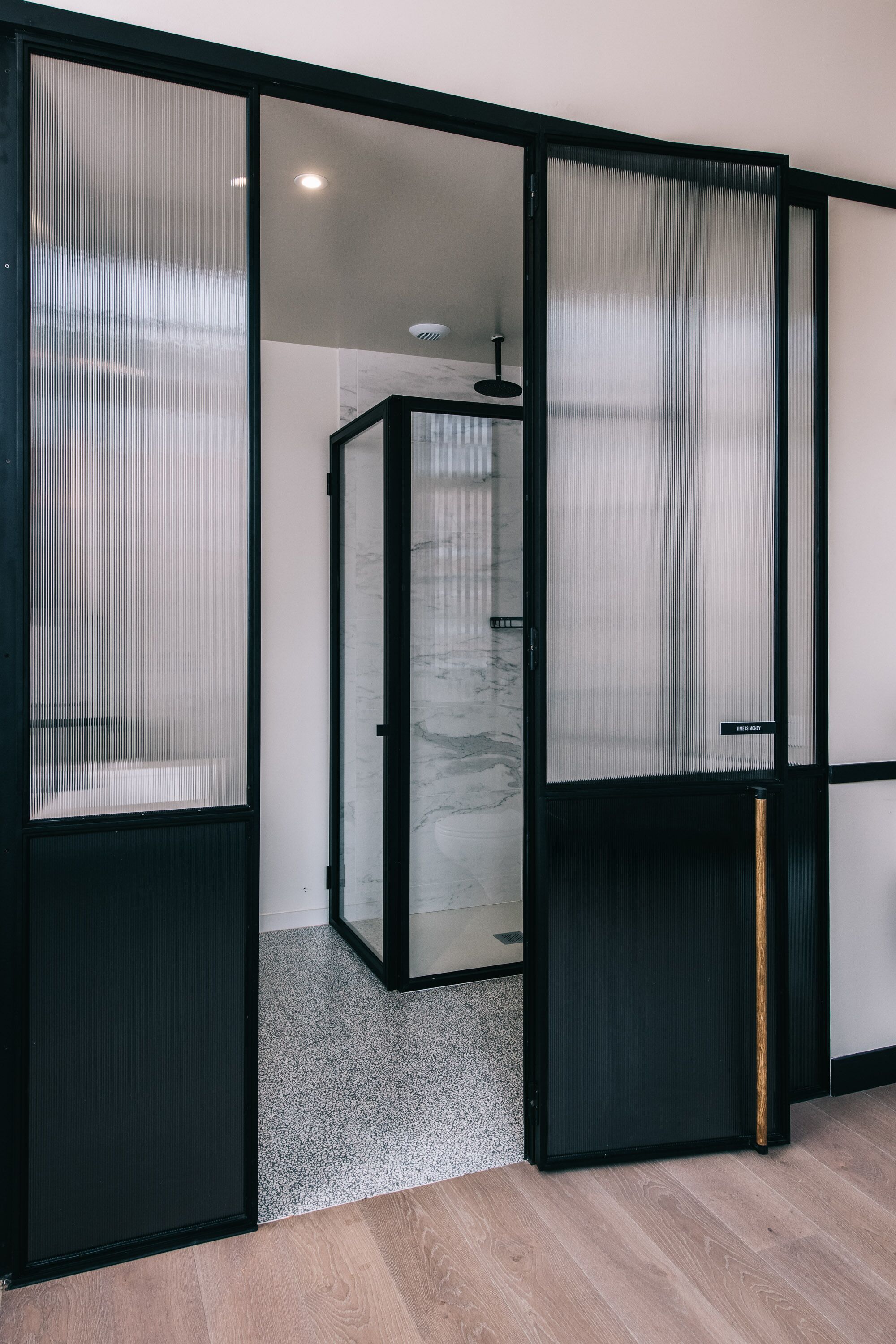 A room with a sliding glass door leading to a bathroom with a marble shower area.
