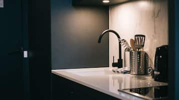 Una cucina moderna con un piano di lavoro bianco, un rubinetto nero, una macchina da caffè e un portauovili.