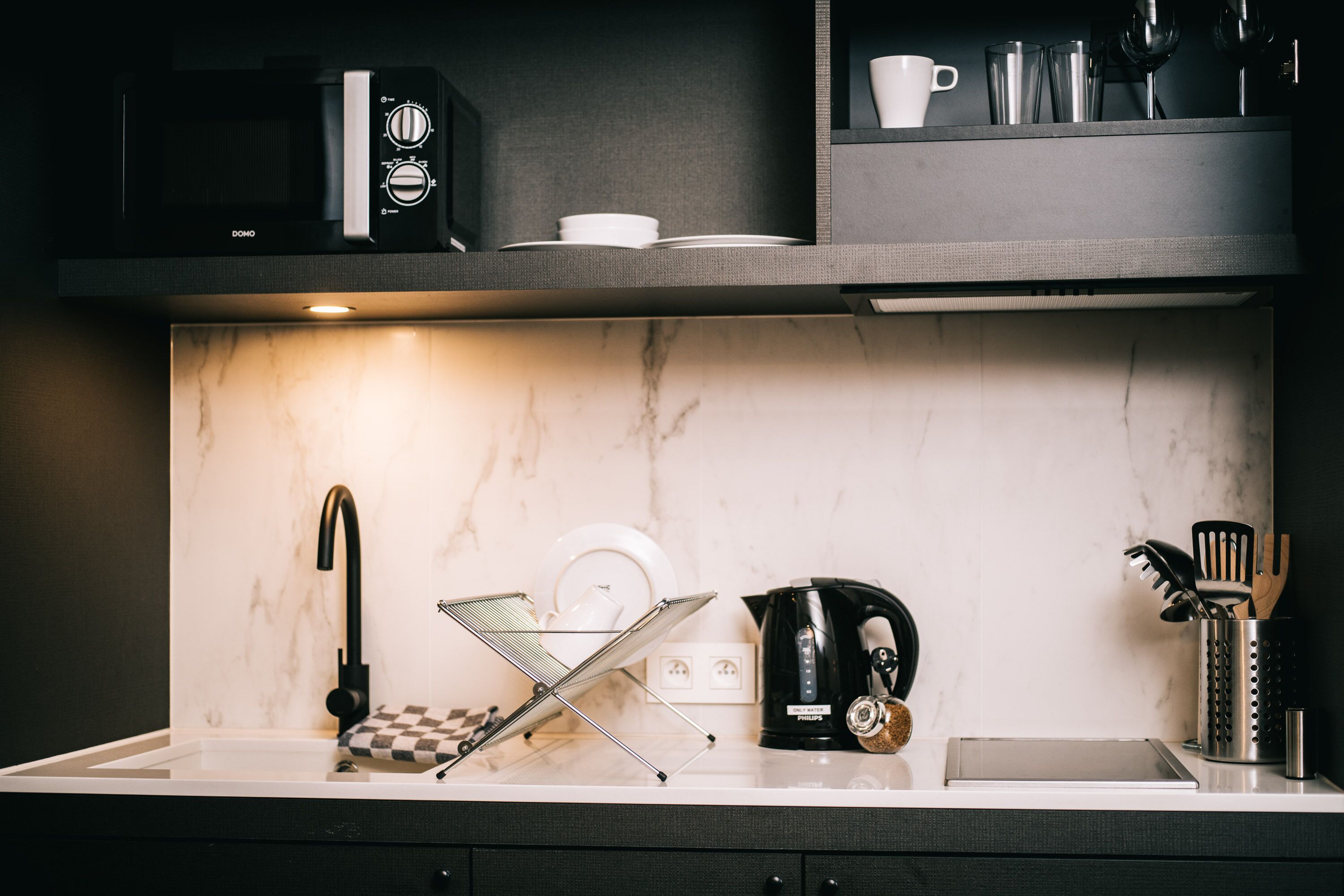 Une cuisine moderne équipée d’un four à micro-ondes encastré, d’une machine à café et d’une bouilloire.