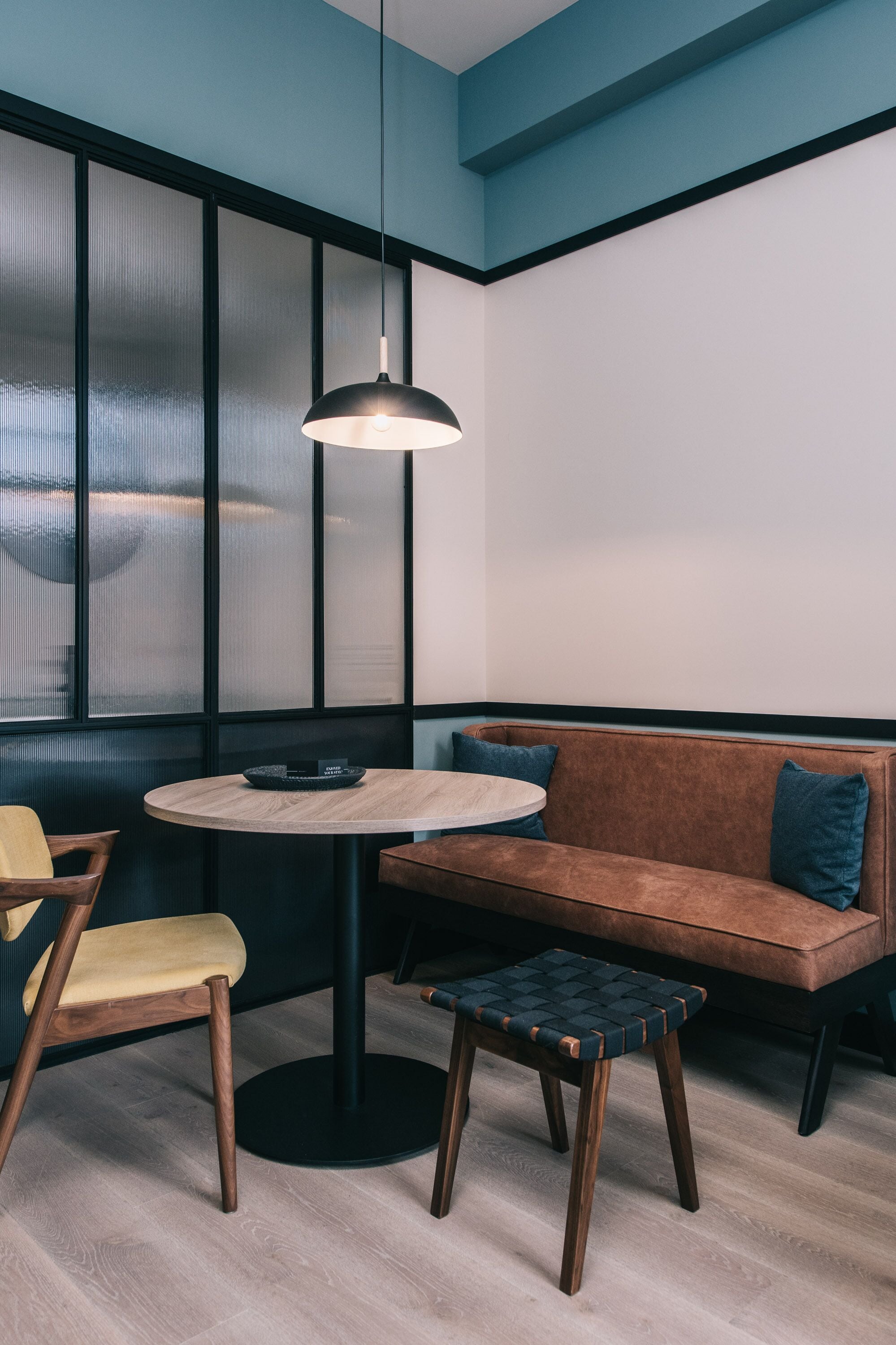 A modern interior with a round table, a brown sofa, and a wooden chair.