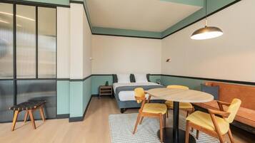 A compact room with a bed, a small table with chairs, a bench, and a sofa.