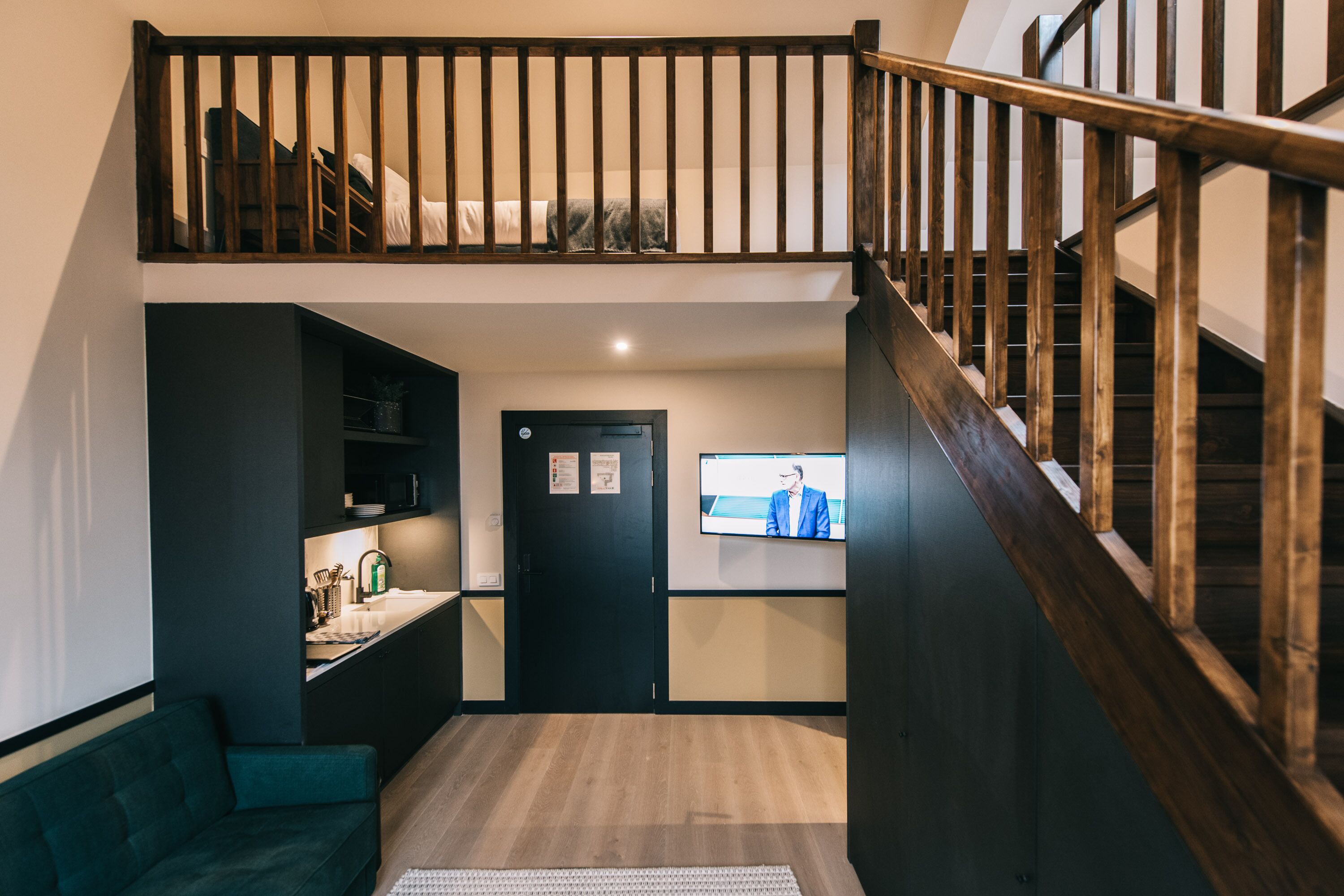 Un intérieur moderne comprenant une chambre en mezzanine, un coin cuisine et un espace de vie.