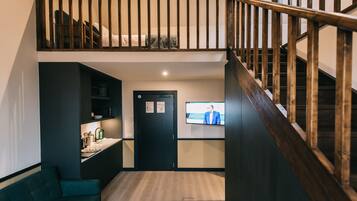 A modern interior with a loft bedroom, a kitchen area, and a living space.