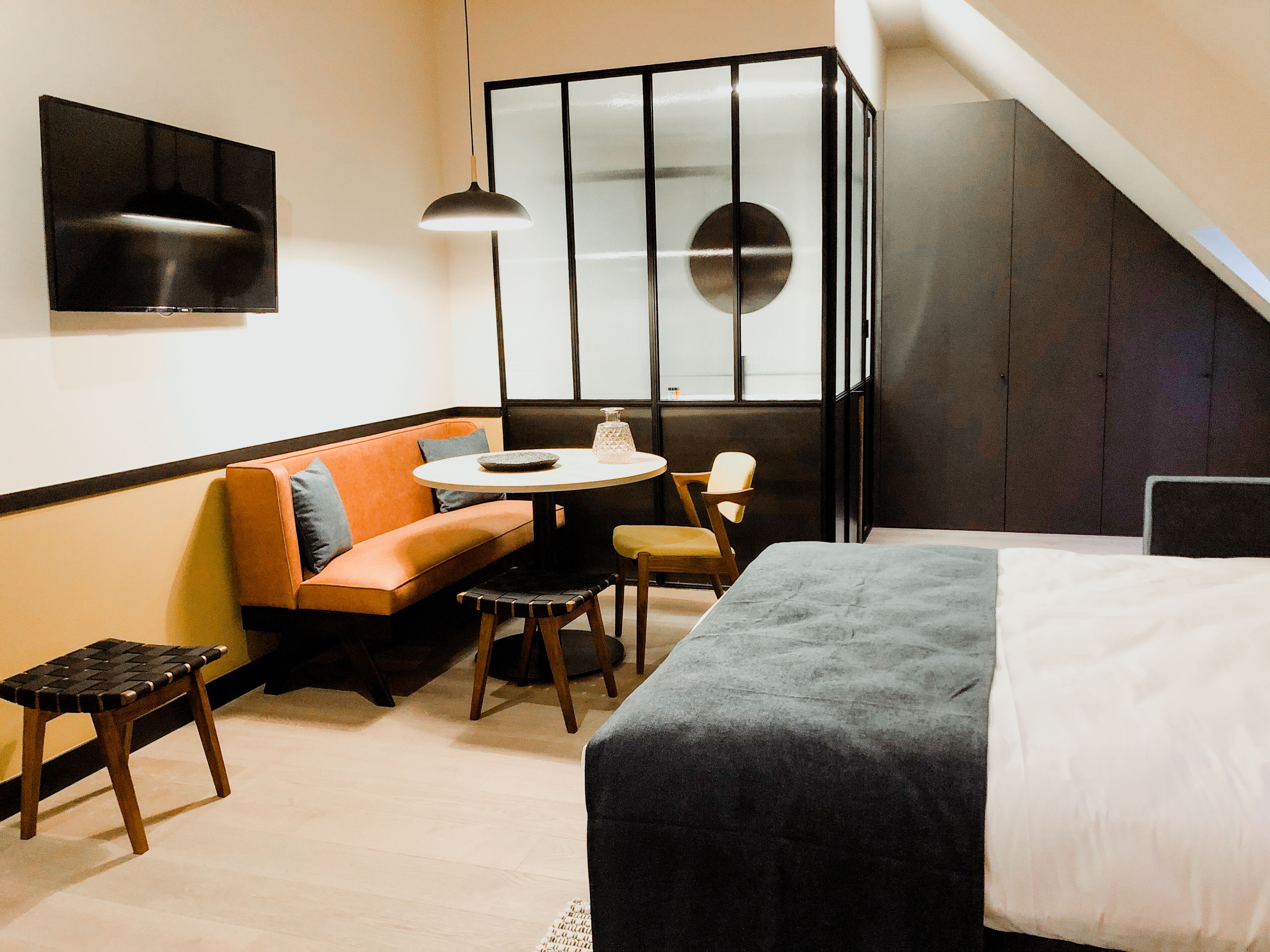 Een moderne hotelkamer met een bed, een bank, een tafeltje en een stoel.
