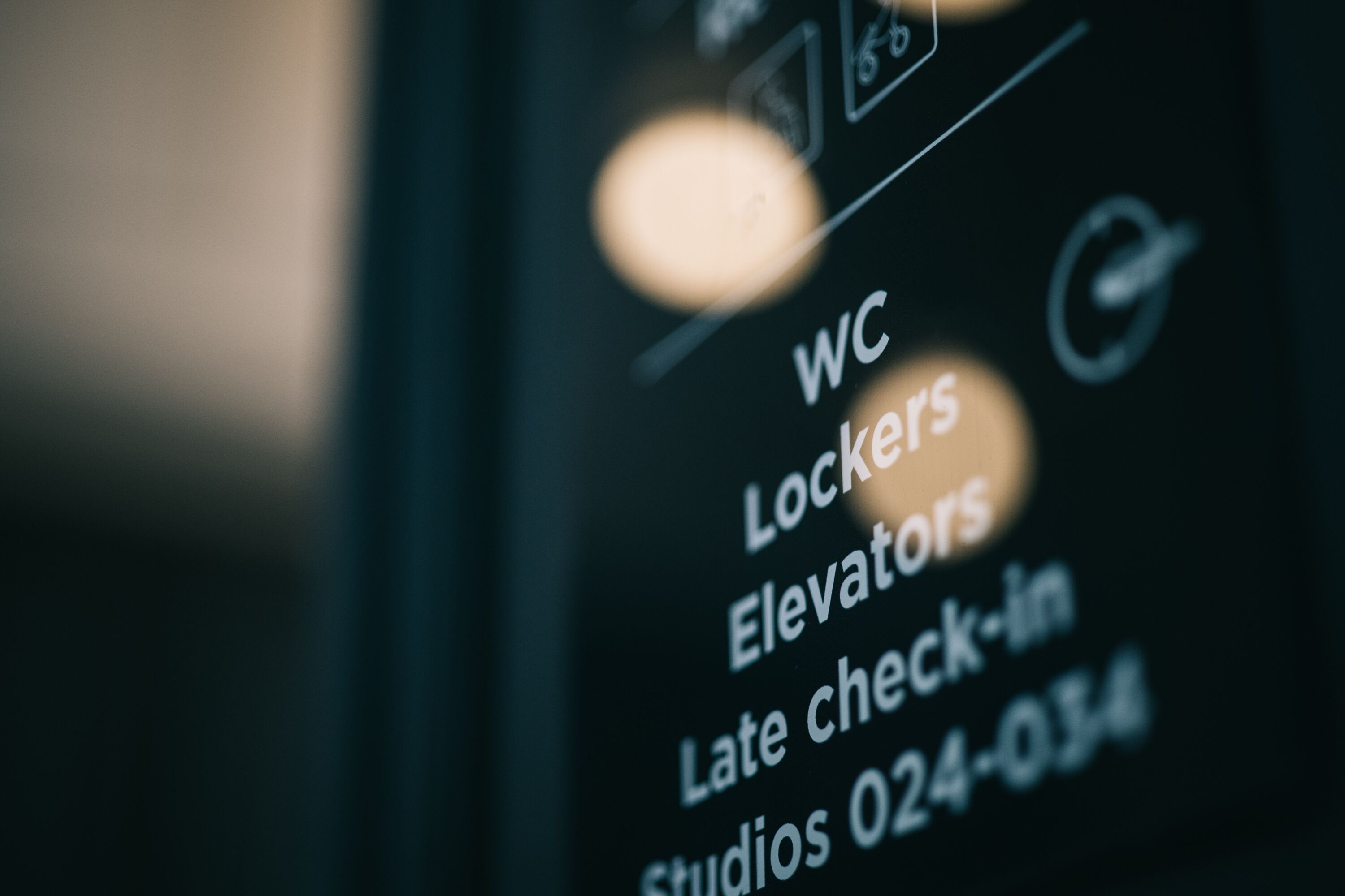 A close-up of a digital display listing amenities such as WC, lockers, elevators, and late check-in.