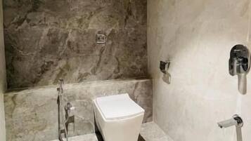 Un baño con pared de mármol, ducha y un inodoro.