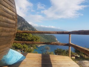 A wooden deck with a view of a coastal landscape, including a body of water and distant mountains. - Mandala Camping - Adults Only (Fethiye)