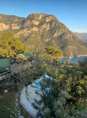 A mountainous landscape with a pool surrounded by trees and a wooden deck. - Mandala Camping - Adults Only (Fethiye)