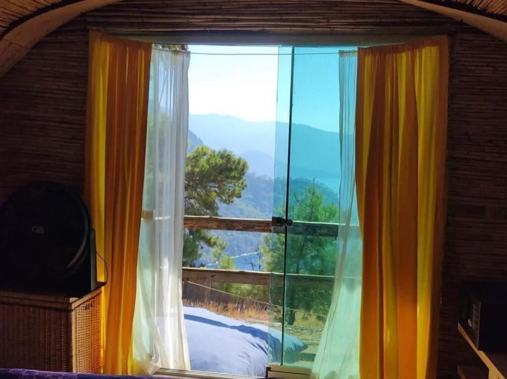 Una habitación con un ventanal grande, una cama y un altavoz.