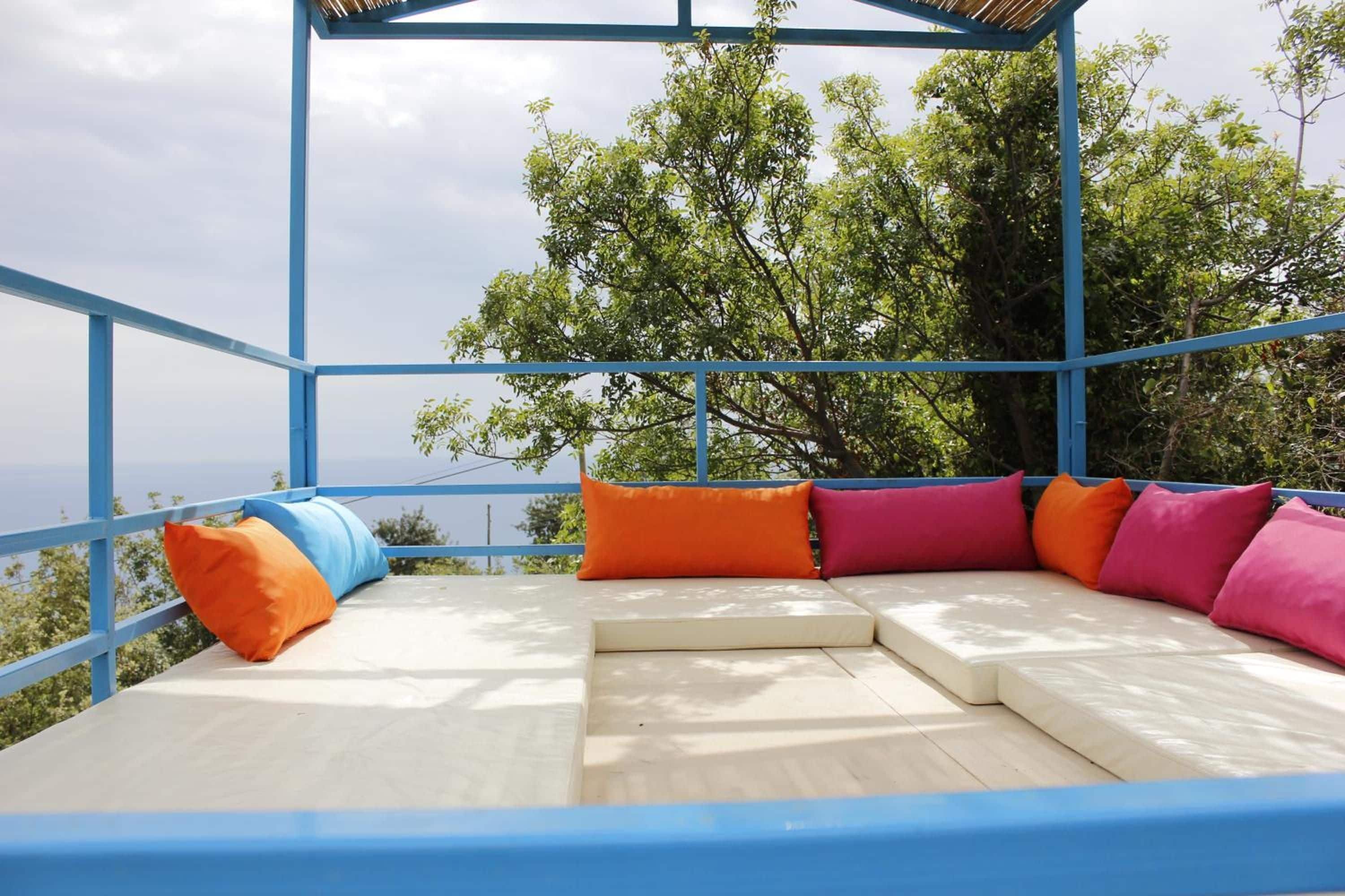 A covered outdoor seating area with a view of trees and the sky.