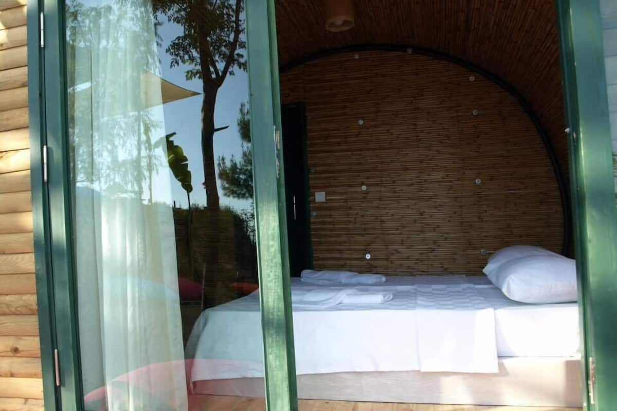 A room with a bed, a window, and a wooden wall.