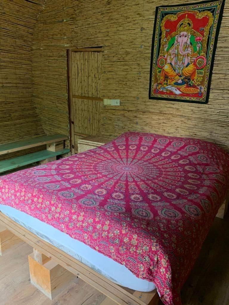 A room with a bed, a wooden bench, and a wall with a framed picture.