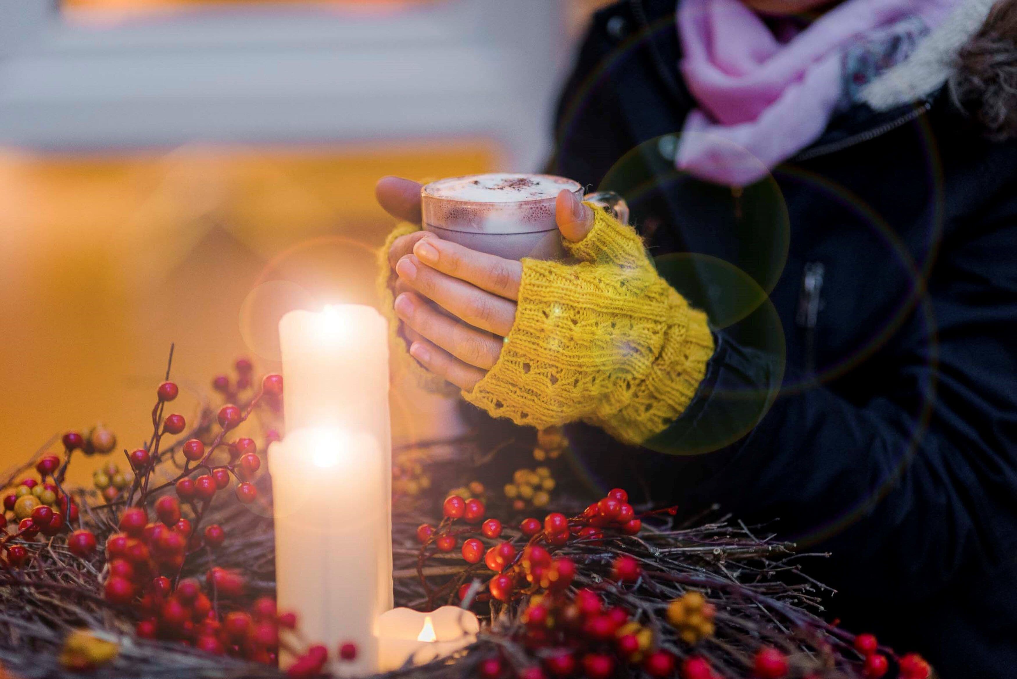 En person håller i ett ljus, och ett tänt ljus syns tydligt i förgrunden.