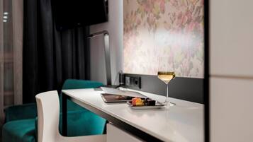 A modern kitchen area with a white countertop, a glass of champagne, and a small plate of food.