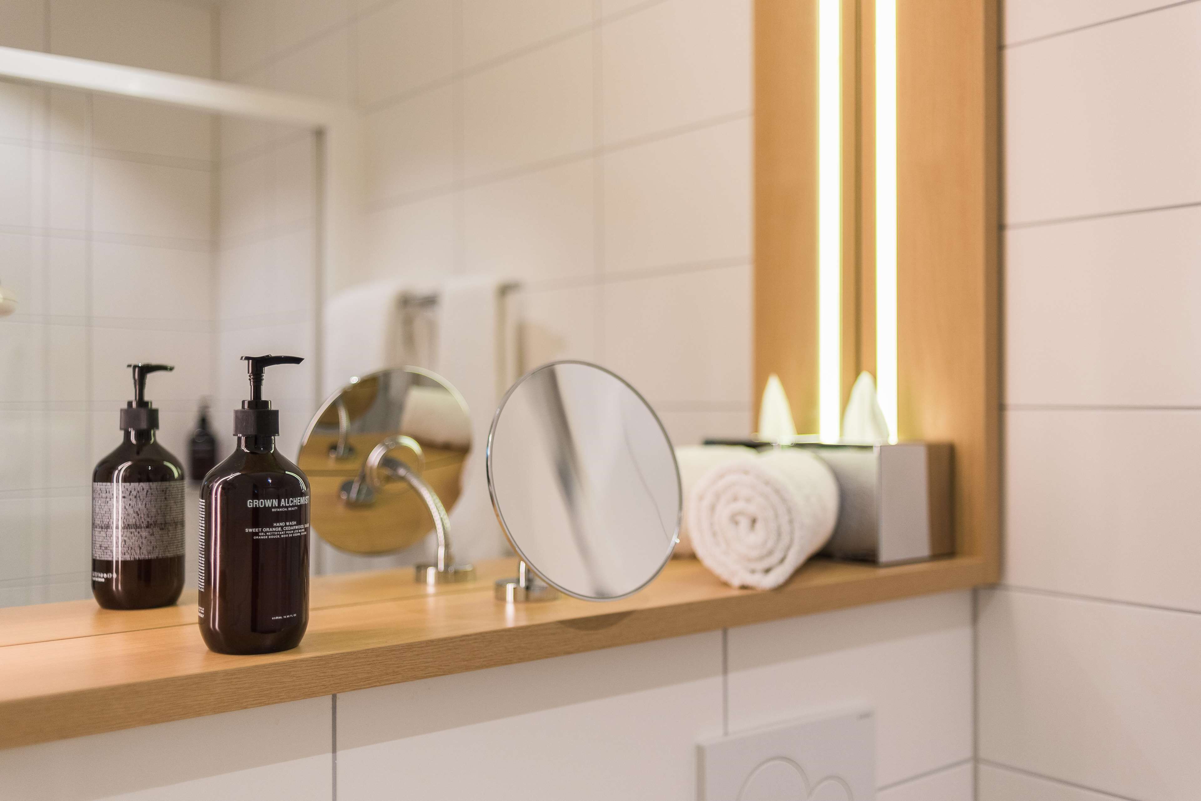 Un meuble-lavabo de salle de bain avec un miroir, deux flacons de produits de soins pour la peau et une serviette.