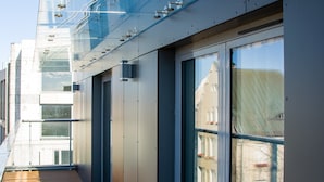 Un couloir doté de portes et de fenêtres en verre, d’un plancher en bois et de rampes en métal.