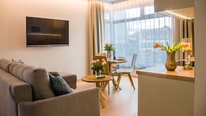 Un salon moderne avec un canapé, une table à manger et un téléviseur fixé au mur.