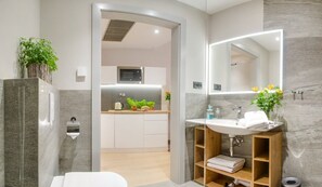 A modern bathroom with a built-in sink, mirror, and shower. - Verde Apartments (Koszalin)
