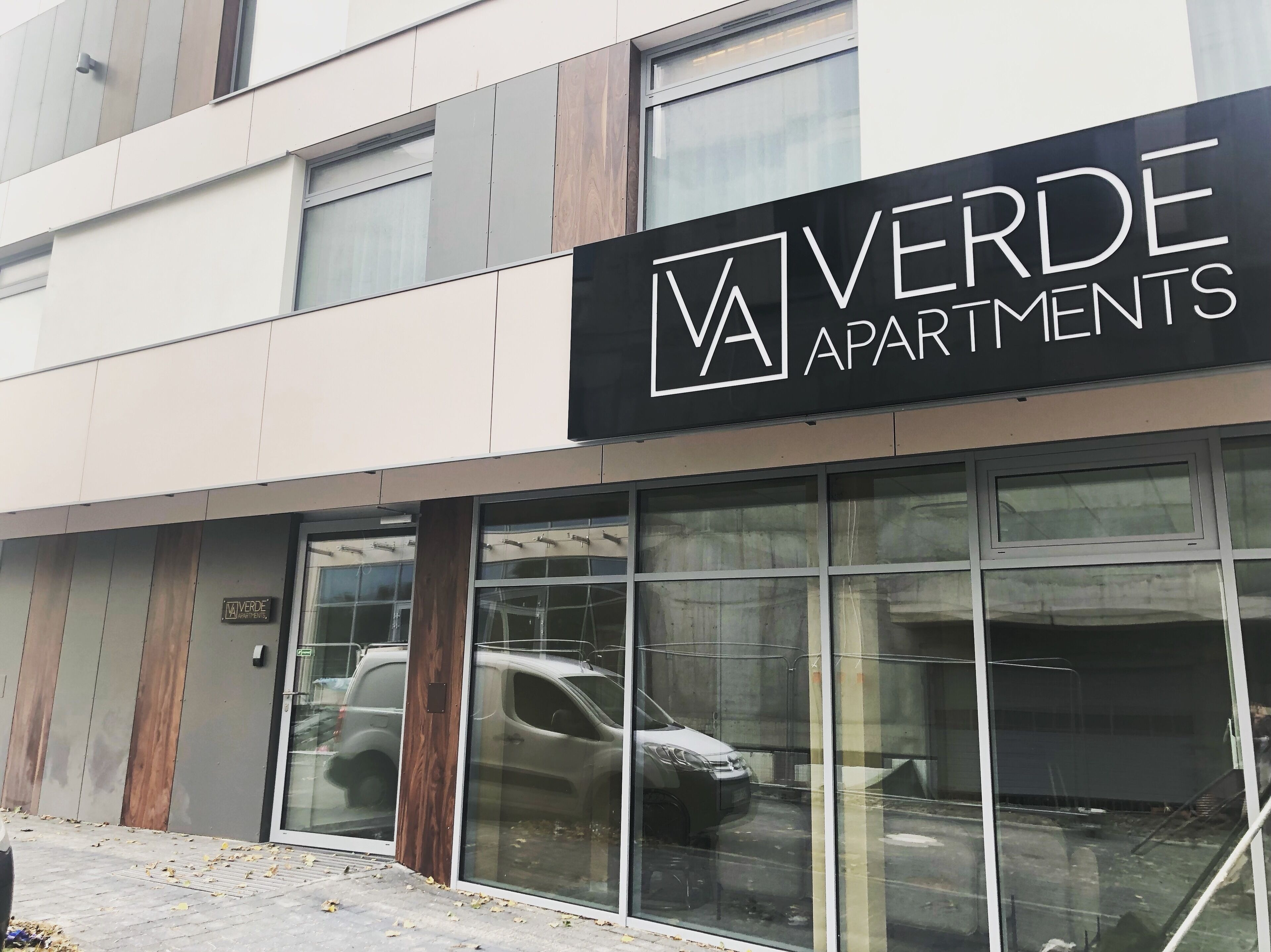 Ein modernes Gebäude mit einem Schild für 'VERDE APARTMENTS'.